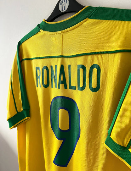 Maillot de foot vintage domicile jaune du Brésil 1998. On peut retrouver l'équipementier Nike. Le maillot est floqué du numéro 9 Ronaldo. Il s'agit d'un maillot authentique d'époque.
