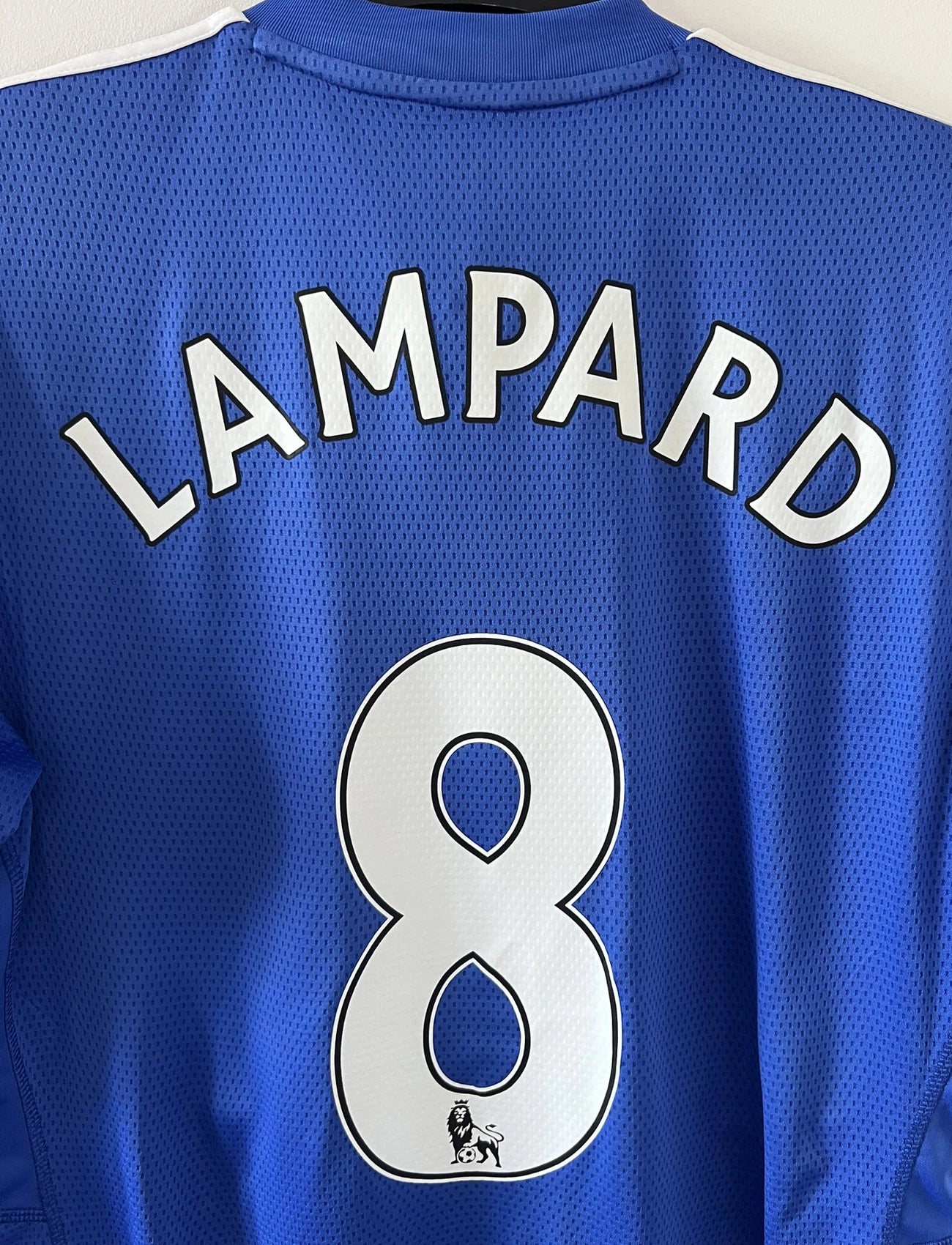 Maillot de foot vinage domicile bleu de chelsea de la saison 2009/2010. On peut retrouver l'équipementier adidas et le sponsor samsung. Le maillot est floqué du numéro 8 Lampard. Il s'agit d'un maillot authentique d'époque comportant les numéros E84291