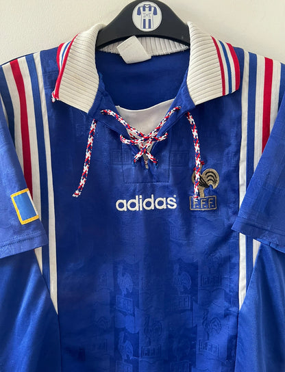 Maillot de foot vintage domicile bleu de l'équipe de france 1996. On peut retrouver l'équipementier Adidas. Il s'agit d'un maillot authentique d'époque.