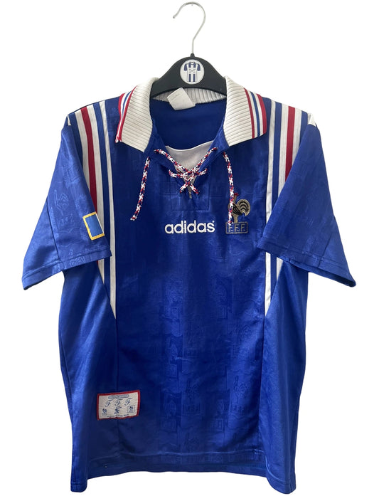 Maillot de foot vintage domicile bleu de l'équipe de france 1996. On peut retrouver l'équipementier Adidas. Il s'agit d'un maillot authentique d'époque.