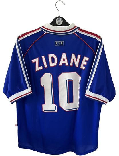 Maillot foot vintage domicile equipe de france 1998 bleu blanc et rouge. On peut retrouver l'équipementier adidas. Le maillot est floqué du numéro 10 Zinedine Zidane. Il s'agit d'un maillot authentique d'époque avec la signature de Zidane en sérigraphié.