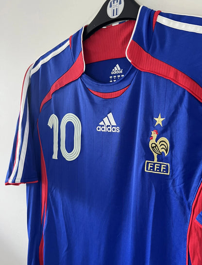 Maillot de foot vintage domicile bleu de l'équipe de france 2006. On peut retrouver l'équipementier adidas. Le maillot est floqué du numéro 10 Zinedine Zidane. Il s'agit d'un maillot authentique comportant l'étiquette 740126.