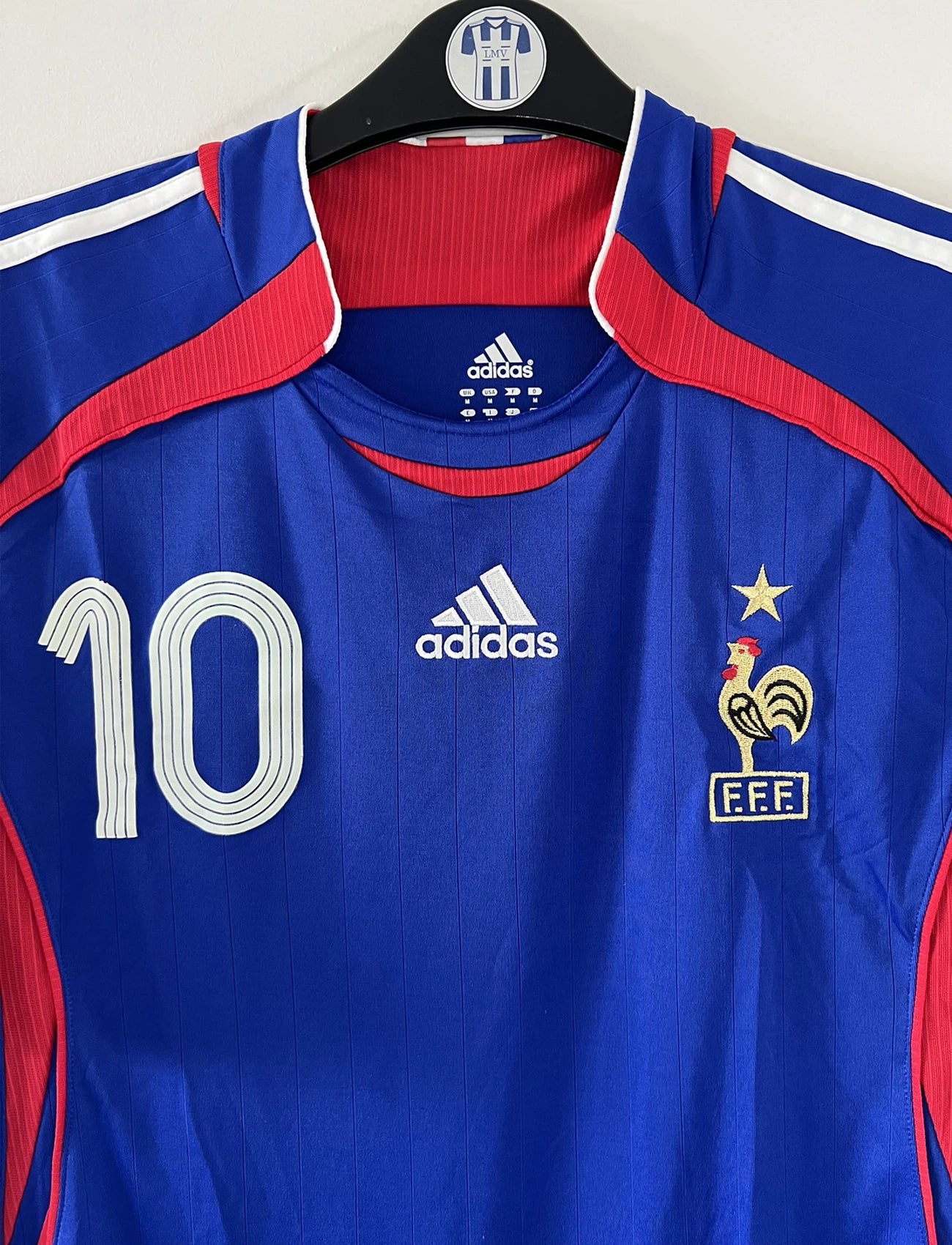 Maillot de foot vintage domicile bleu de l'équipe de france 2006. On peut retrouver l'équipementier adidas. Le maillot est floqué du numéro 10 Zinedine Zidane. Il s'agit d'un maillot authentique comportant l'étiquette 740126.