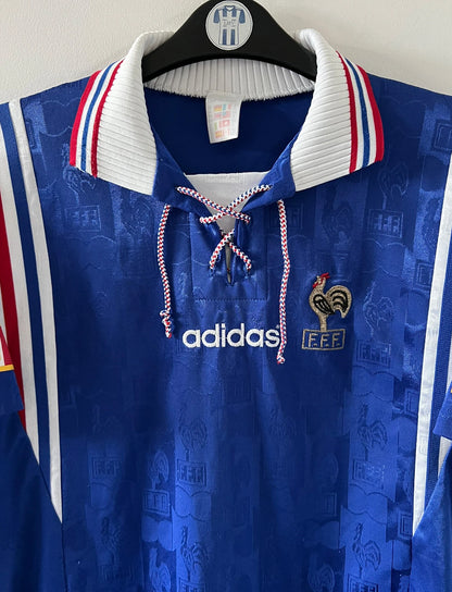 Maillot de foot vintage domicile bleu de l'équipe de france 1996. On peut retrouver l'équipementier Adidas. Il s'agit d'un maillot authentique d'époque.