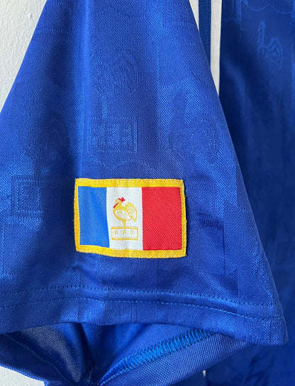 Maillot de foot vintage domicile bleu de l'équipe de france 1996. On peut retrouver l'équipementier Adidas. Il s'agit d'un maillot authentique d'époque.