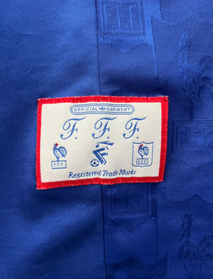 Maillot de foot vintage domicile bleu de l'équipe de france 1996. On peut retrouver l'équipementier Adidas. Il s'agit d'un maillot authentique d'époque.