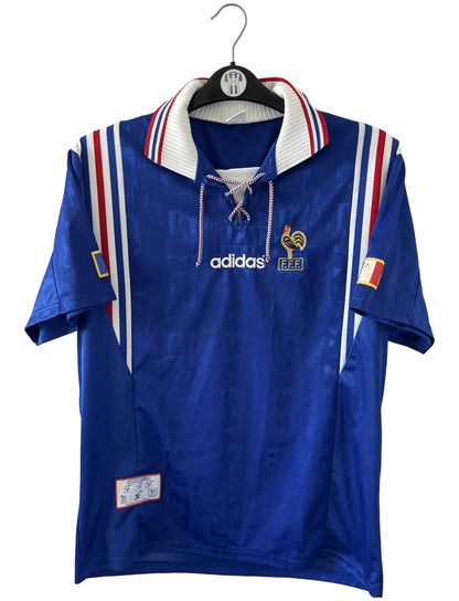 Maillot de foot vintage domicile bleu de l'équipe de france 1996. On peut retrouver l'équipementier Adidas. Il s'agit d'un maillot authentique d'époque.