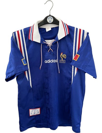 Maillot de foot vintage domicile bleu de l'équipe de france 1996. On peut retrouver l'équipementier Adidas. Il s'agit d'un maillot authentique d'époque.
