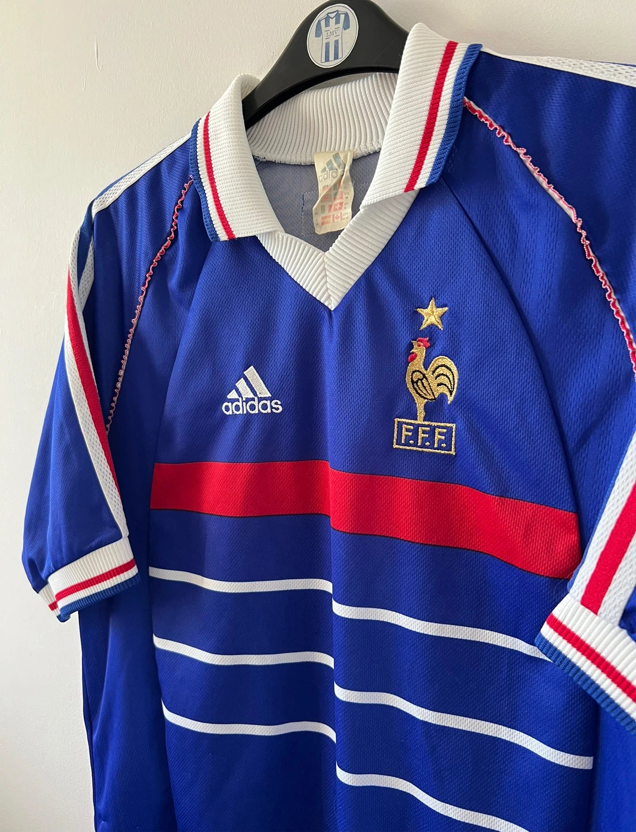 Maillot de foot vintage domicile bleu blanc et rouge de l'équipe de france 1998. On peut retrouver l'équipementier Adidas. Il s'agit d'un maillot authentique d'époque.