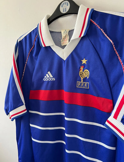 Maillot de foot vintage domicile bleu blanc et rouge de l'équipe de france 1998. On peut retrouver l'équipementier Adidas. Il s'agit d'un maillot authentique d'époque.