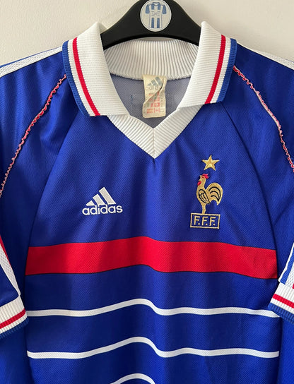 Maillot de foot vintage domicile bleu blanc et rouge de l'équipe de france 1998. On peut retrouver l'équipementier Adidas. Il s'agit d'un maillot authentique d'époque.