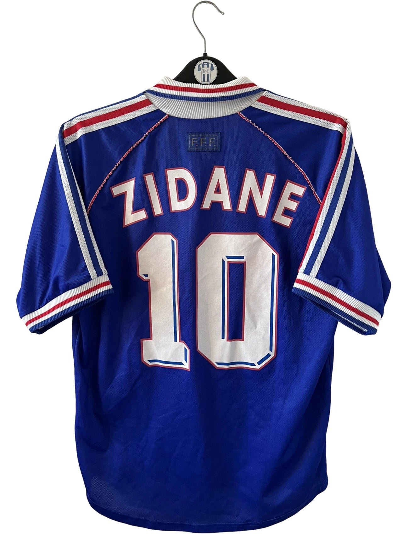 Maillot de foot vintage domicile bleu de l'Equipe de France 1998. On peut retrouver l'équipementier Adidas. Le maillot est floqué du numéro 10 Zinedine Zidane. Il s'agit d'un maillot authentique d'époque.