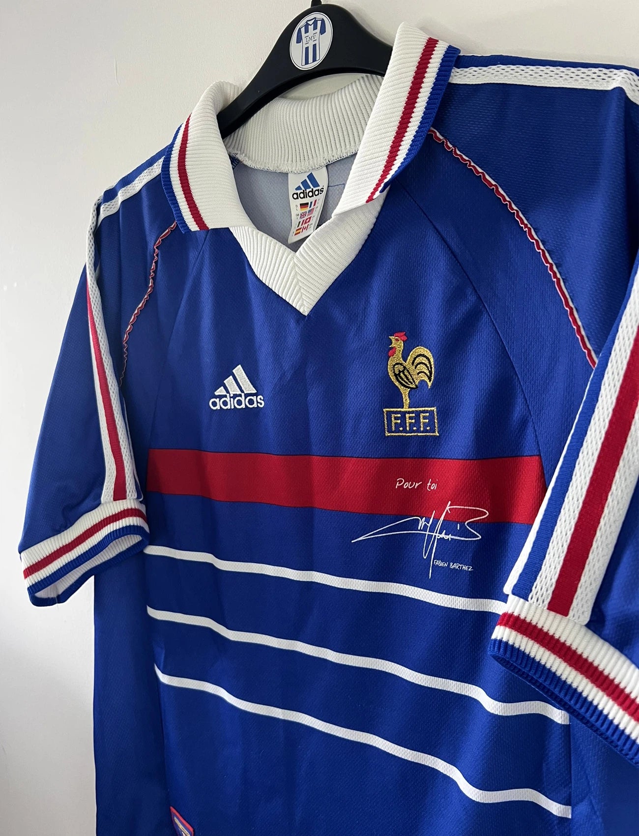 Maillot de foot vintage domicile bleu de l'équipe de france 1998. On peut retrouver l'équipementier adidas. Le maillot est signé avec la mention pour toi fabien barthez. Il s'agit d'un maillot authentique d'époque.