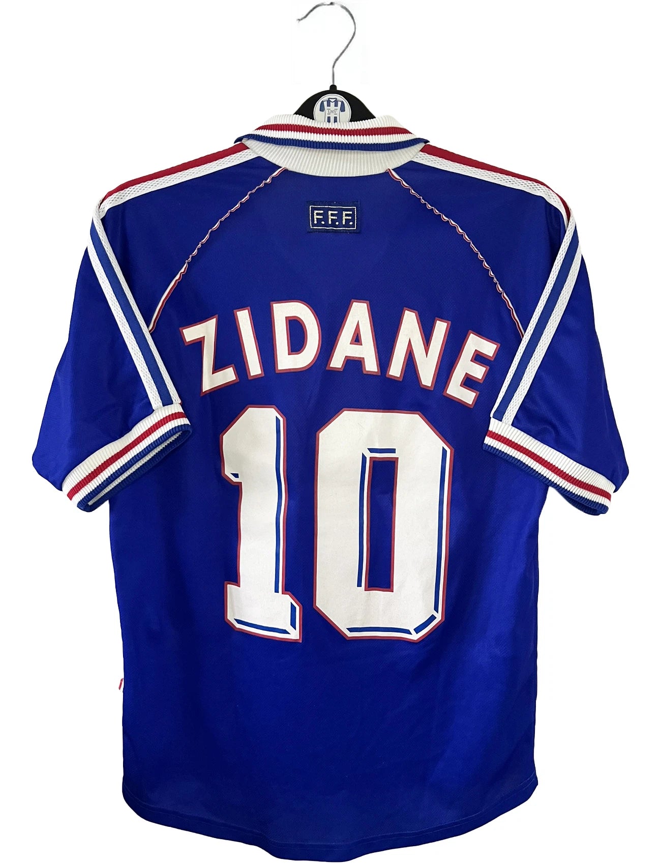 Maillot de foot vintage domicile bleu de l'équipe de france 1998. On peut retrouver l'équipementier Adidas. Le maillot est floqué du numéro 10 Zinedine Zidane. Il s'agit d'un maillot authentique d'époque.