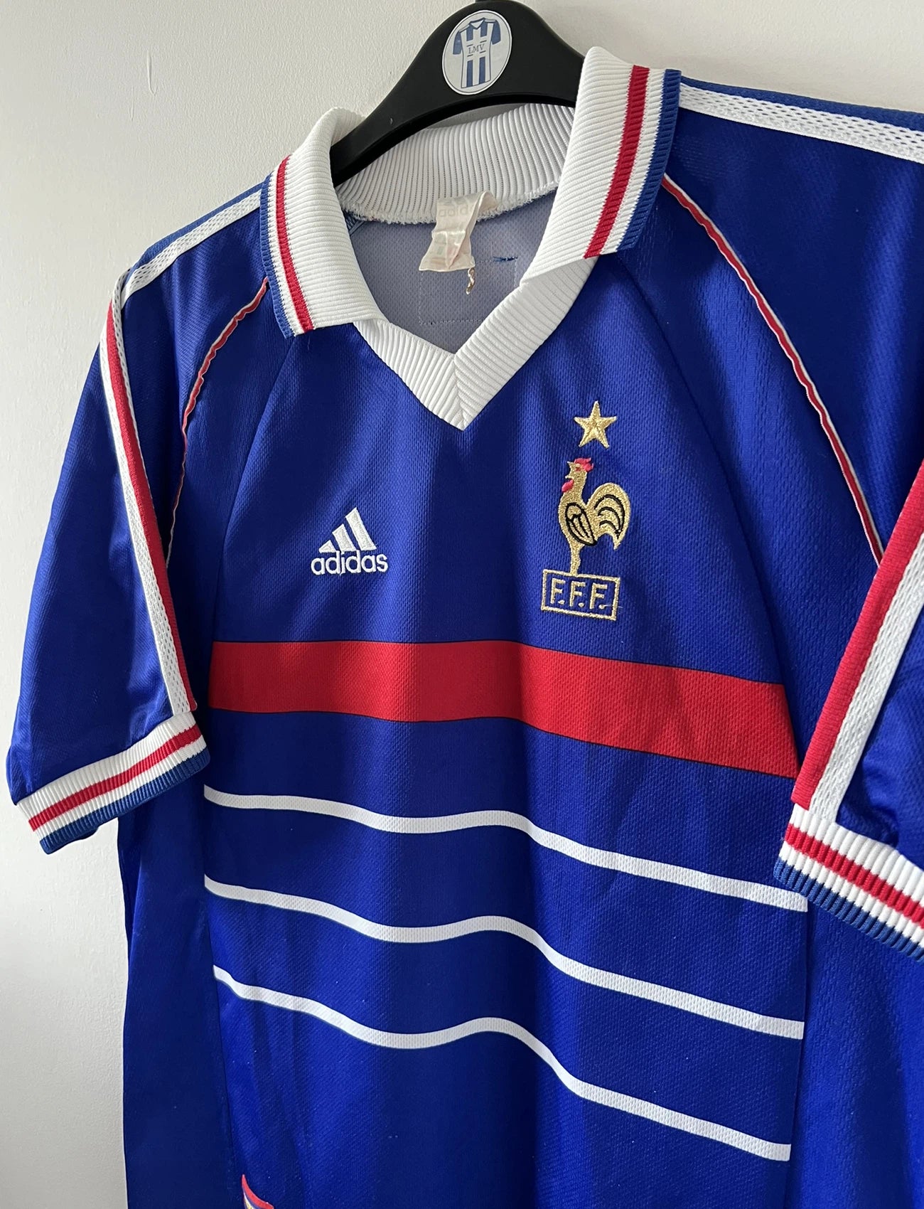 Maillot de foot vintage domicile bleu blanc et rouge de l'équipe de france 1998. On peut retrouver l'équipementier Adidas. Le maillot est floqué du numéro 10 Zinedine Zidane. Il s'agit d'un maillot authentique d'époque.