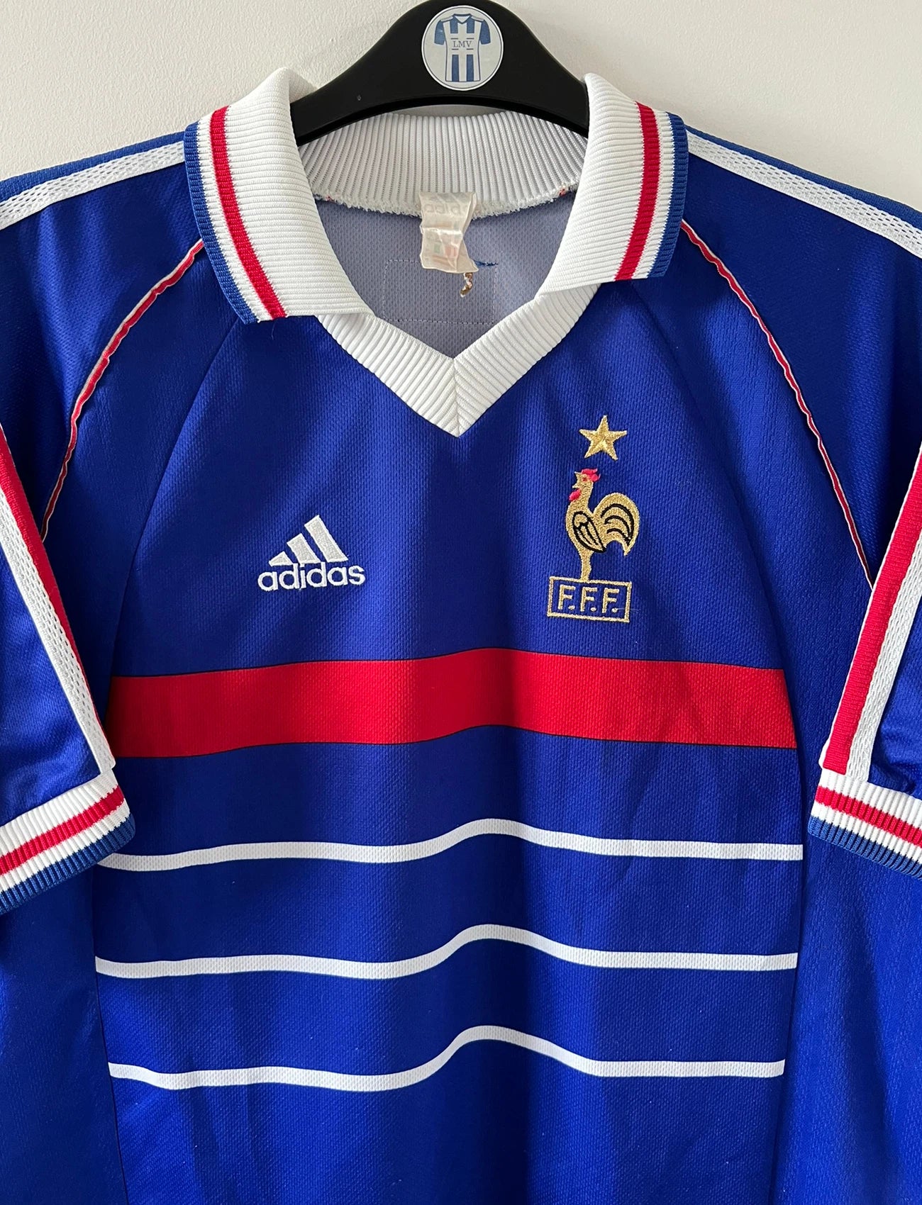 Maillot de foot vintage domicile bleu blanc et rouge de l'équipe de france 1998. On peut retrouver l'équipementier Adidas. Le maillot est floqué du numéro 10 Zinedine Zidane. Il s'agit d'un maillot authentique d'époque.