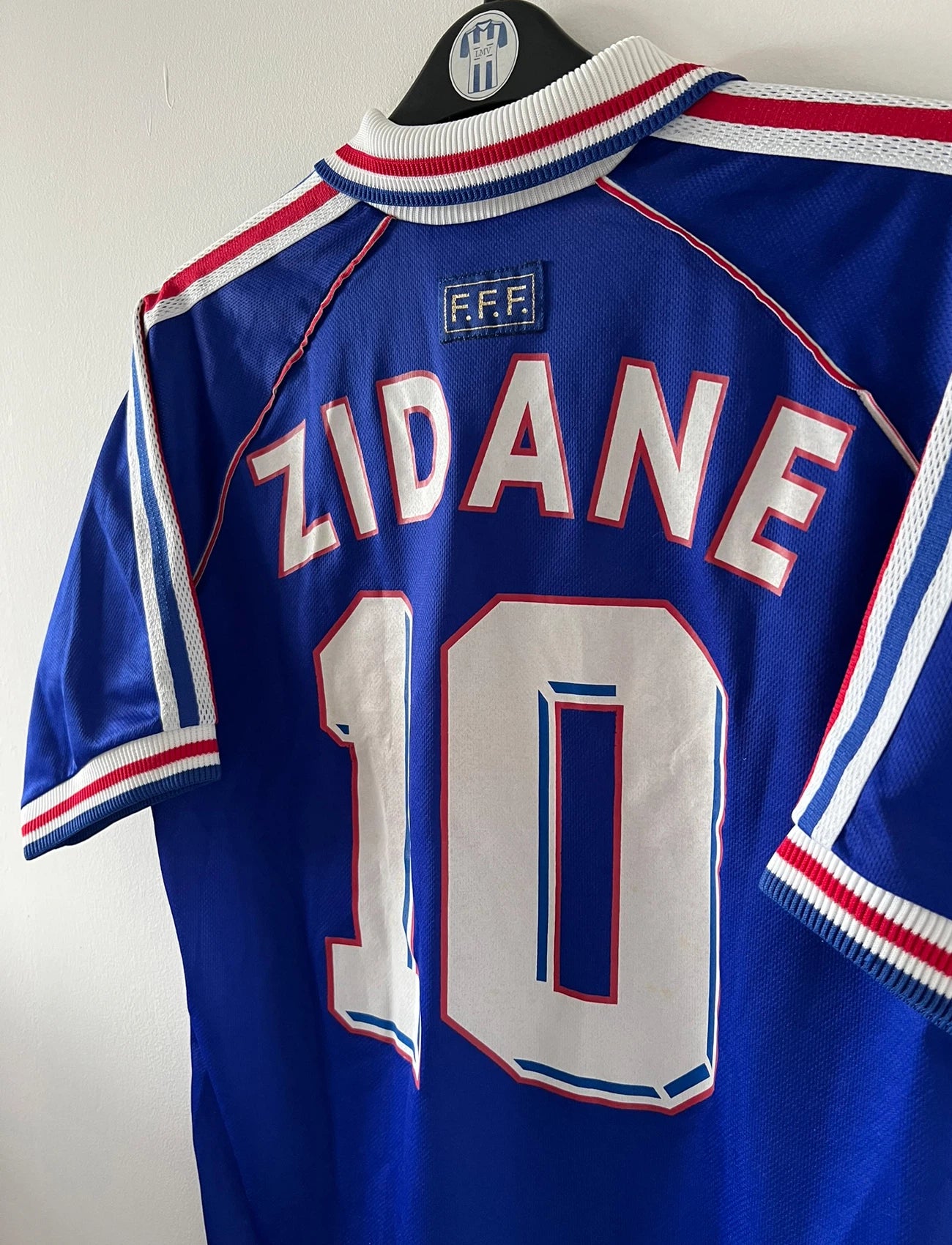 Maillot de foot vintage domicile bleu blanc et rouge de l'équipe de france 1998. On peut retrouver l'équipementier Adidas. Le maillot est floqué du numéro 10 Zinedine Zidane. Il s'agit d'un maillot authentique d'époque.
