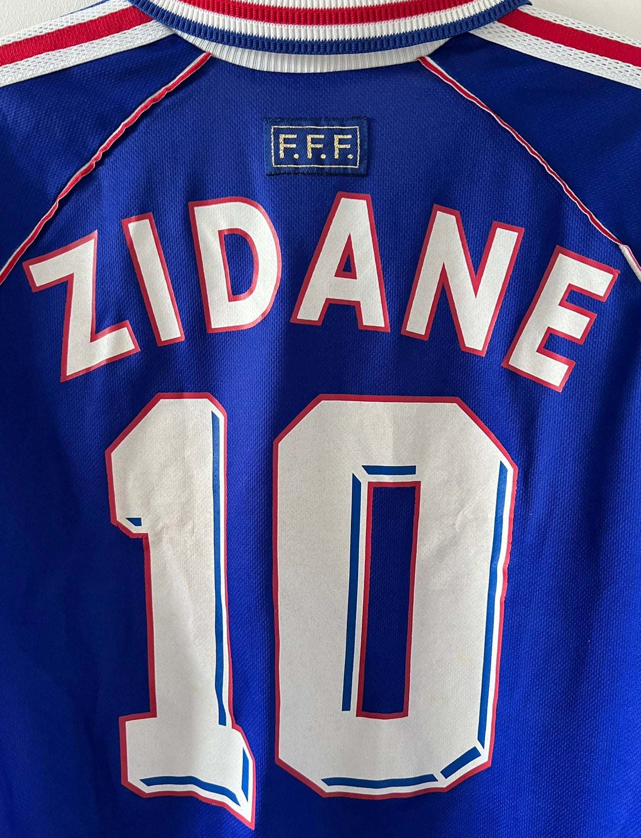 Maillot de foot vintage domicile bleu blanc et rouge de l'équipe de france 1998. On peut retrouver l'équipementier Adidas. Le maillot est floqué du numéro 10 Zinedine Zidane. Il s'agit d'un maillot authentique d'époque.