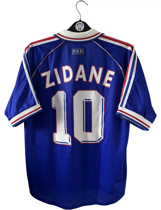 Maillot de foot vintage domicile bleu blanc et rouge de l'équipe de france 1998. On peut retrouver l'équipementier Adidas. Le maillot est floqué du numéro 10 Zinedine Zidane. Il s'agit d'un maillot authentique d'époque.