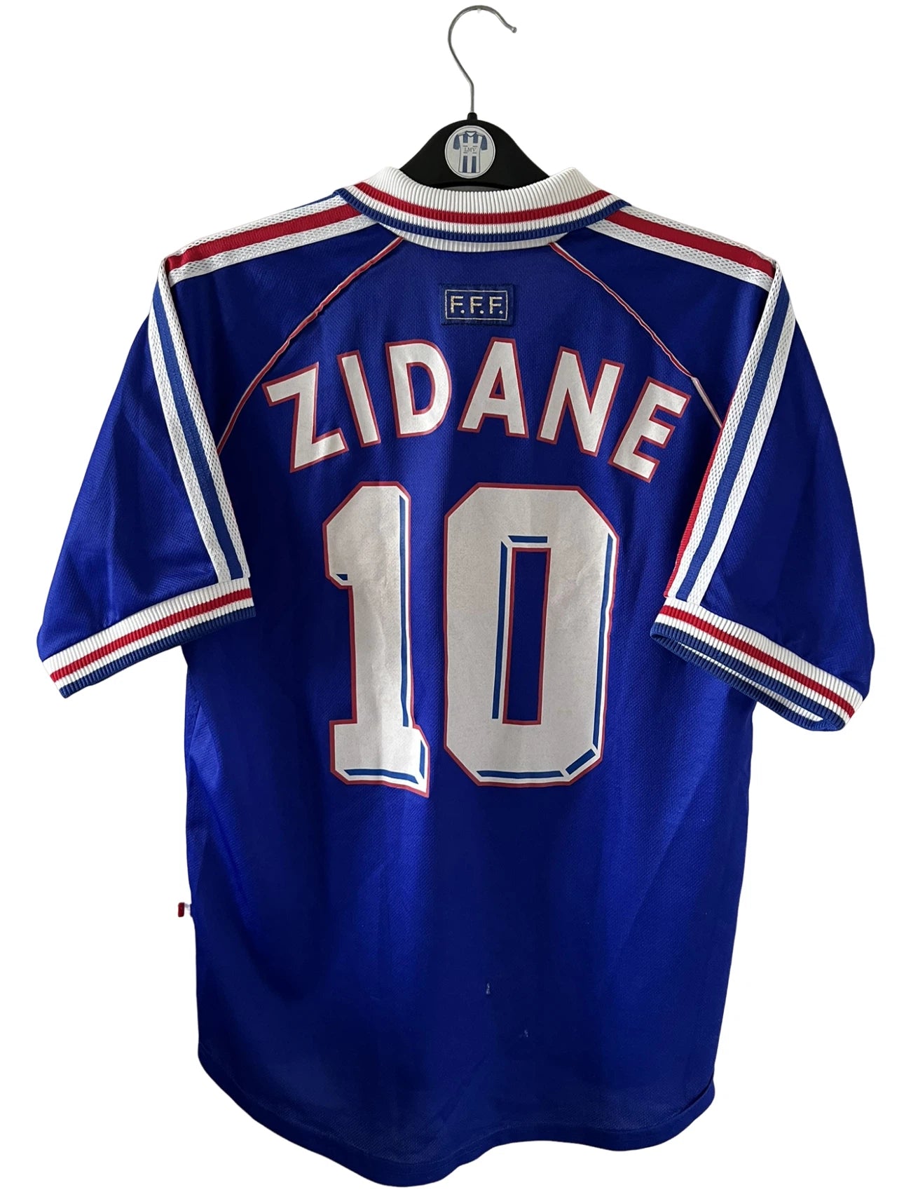 Maillot de foot vintage domicile bleu blanc et rouge de l'équipe de france 1998. On peut retrouver l'équipementier Adidas. Le maillot est floqué du numéro 10 Zinedine Zidane. Il s'agit d'un maillot authentique d'époque.