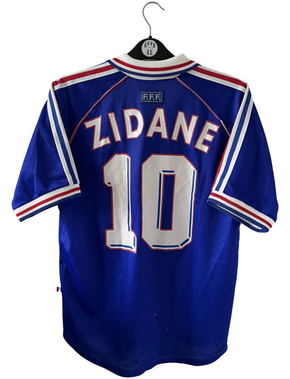 Maillot de foot vintage domicile bleu blanc et rouge de l'équipe de france 1998. On peut retrouver l'équipementier Adidas. Le maillot est floqué du numéro 10 Zinedine Zidane. Il s'agit d'un maillot authentique d'époque.