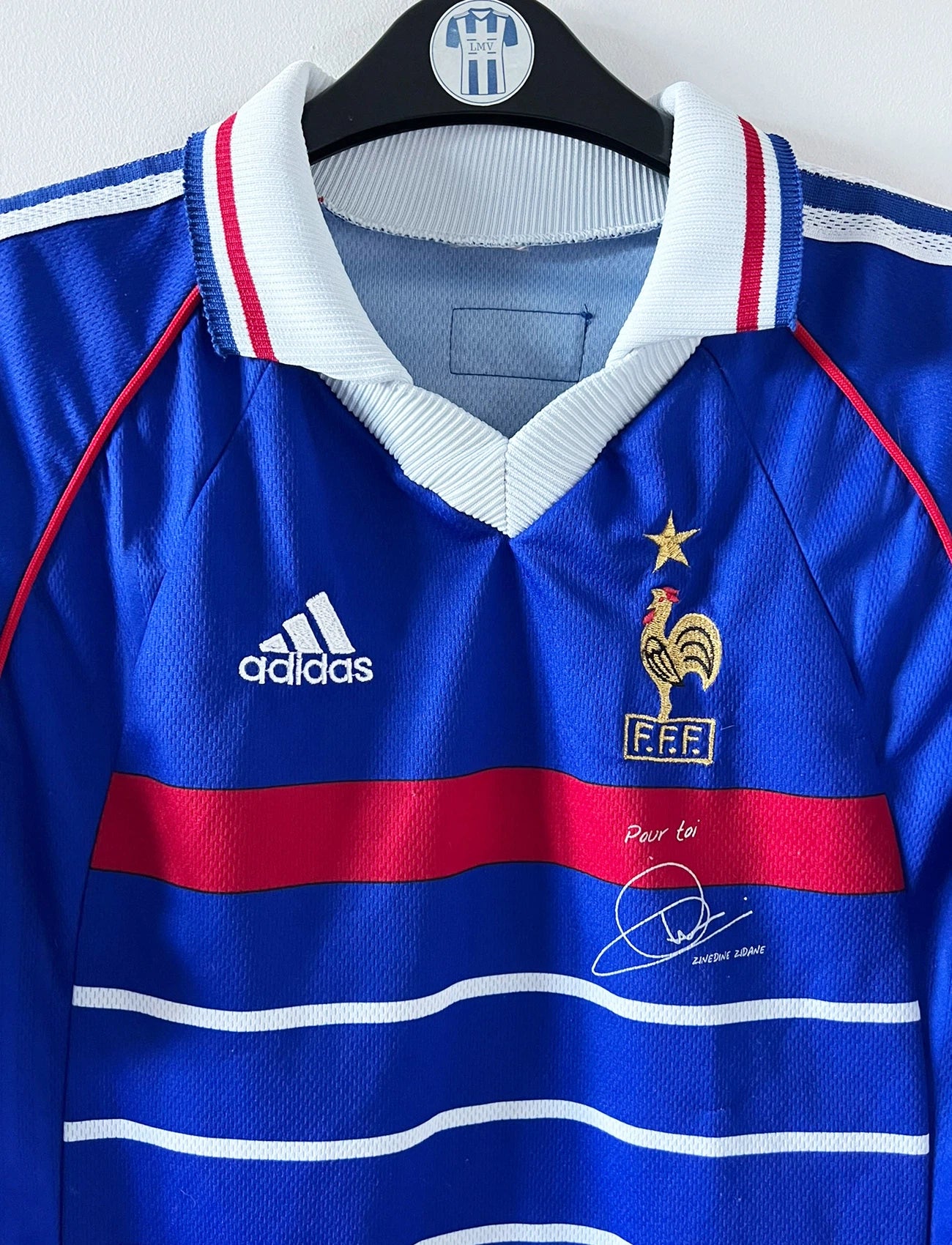 Maillot de foot vintage domicile bleu de l'équipe de France 1998. On peut retrouver l'équipementier Adidas, la signature et le flocage de Zinedine Zidane. Il s'agit d'une magnifique pièce de collection.
