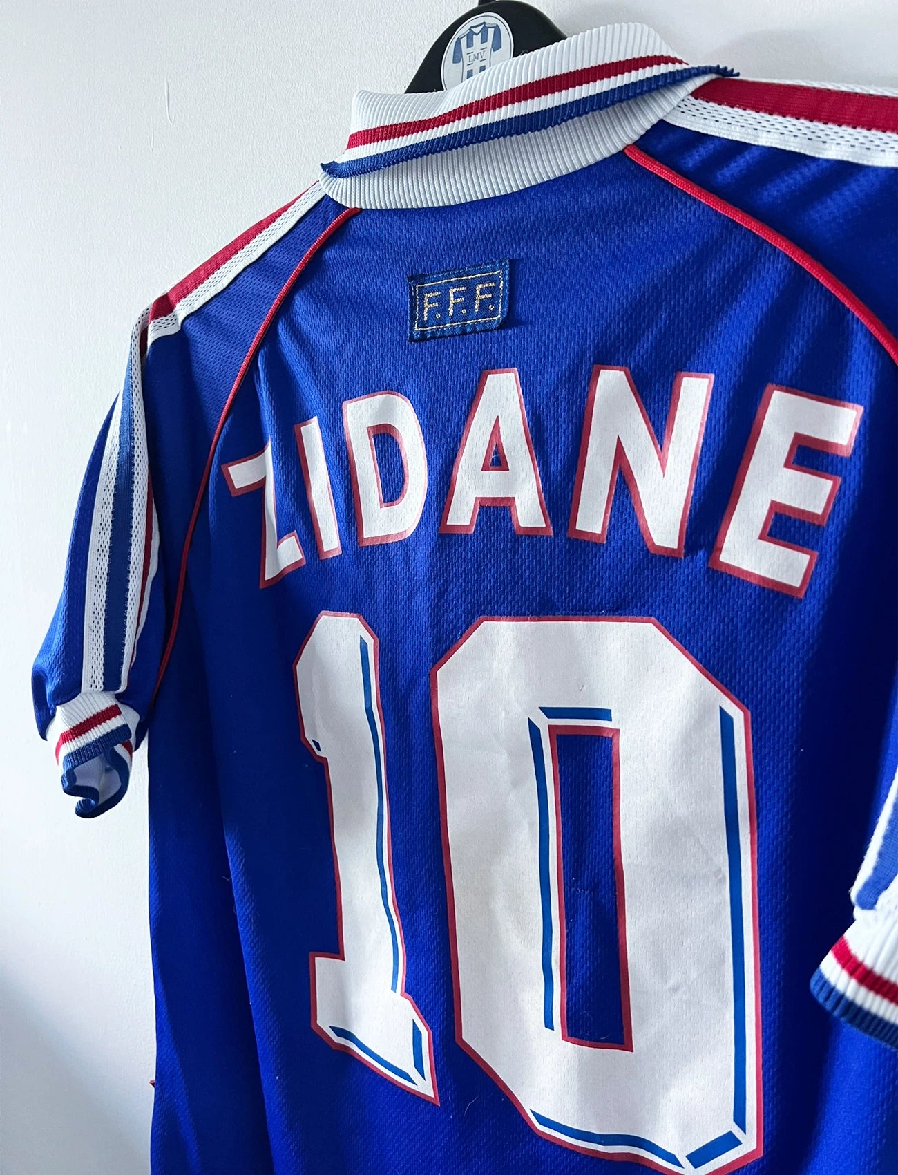 Maillot de foot vintage domicile bleu de l'équipe de France 1998. On peut retrouver l'équipementier Adidas, la signature et le flocage de Zinedine Zidane. Il s'agit d'une magnifique pièce de collection.