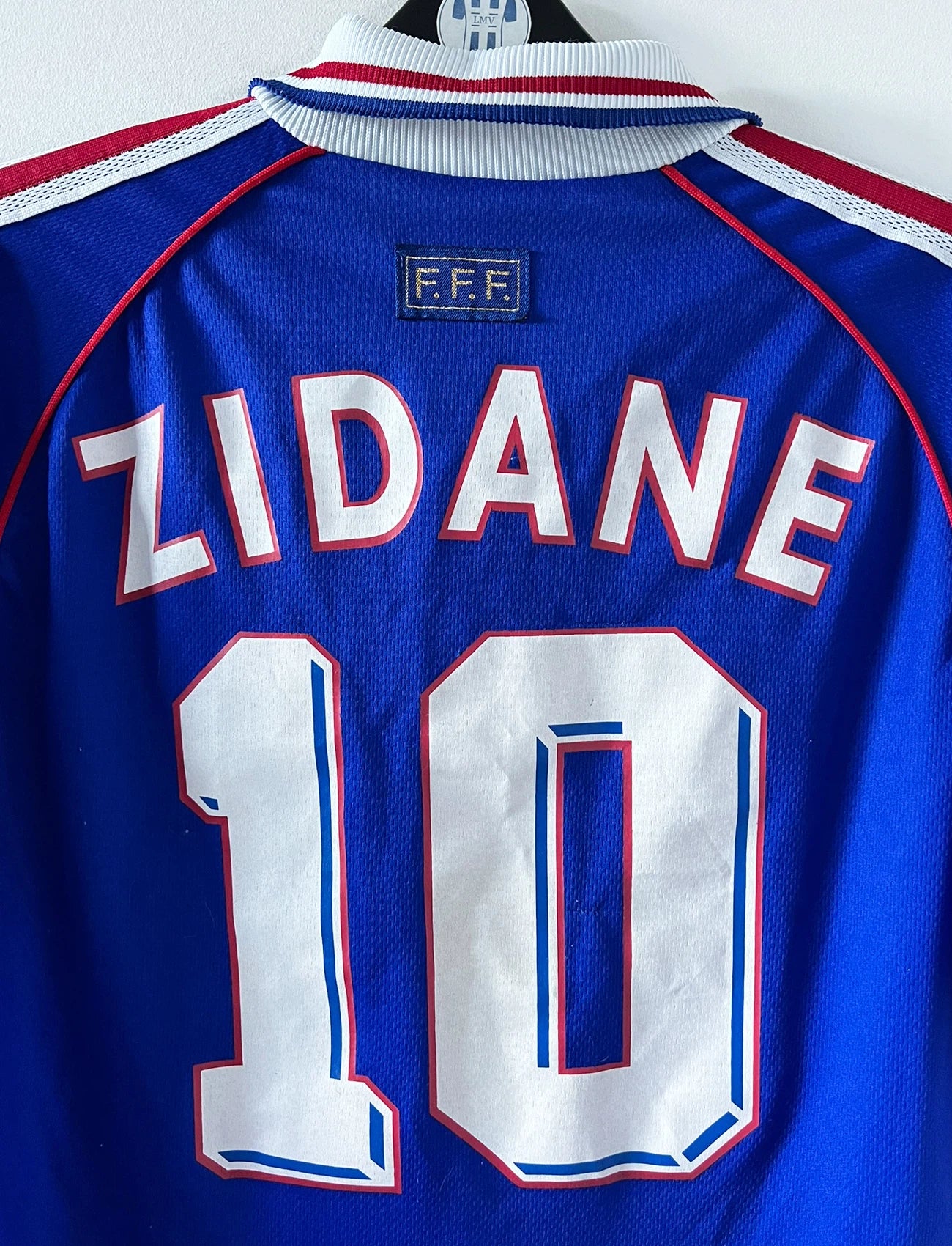 Maillot de foot vintage domicile bleu de l'équipe de France 1998. On peut retrouver l'équipementier Adidas, la signature et le flocage de Zinedine Zidane. Il s'agit d'une magnifique pièce de collection.