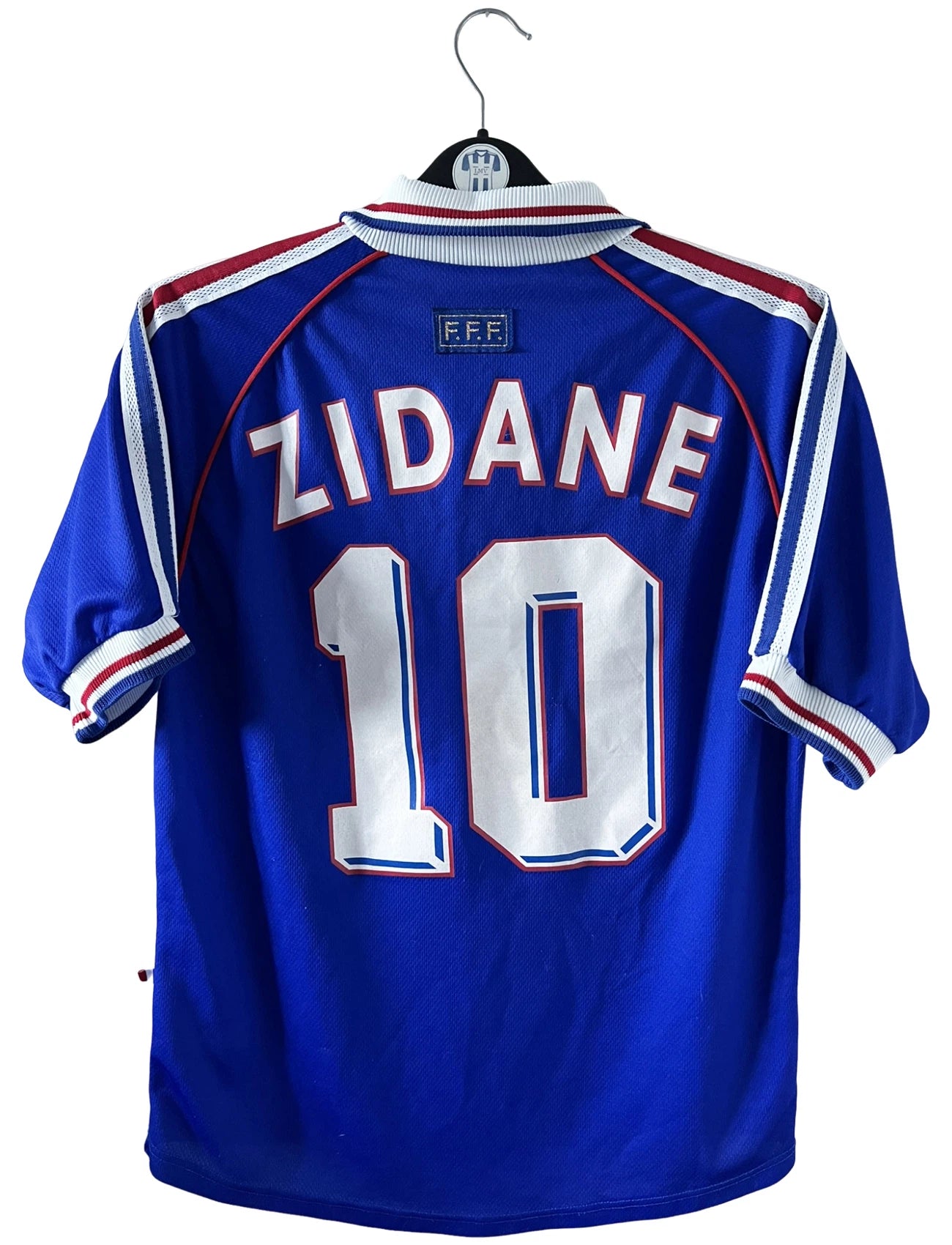 Maillot de foot vintage domicile bleu de l'équipe de France 1998. On peut retrouver l'équipementier Adidas, la signature et le flocage de Zinedine Zidane. Il s'agit d'une magnifique pièce de collection.