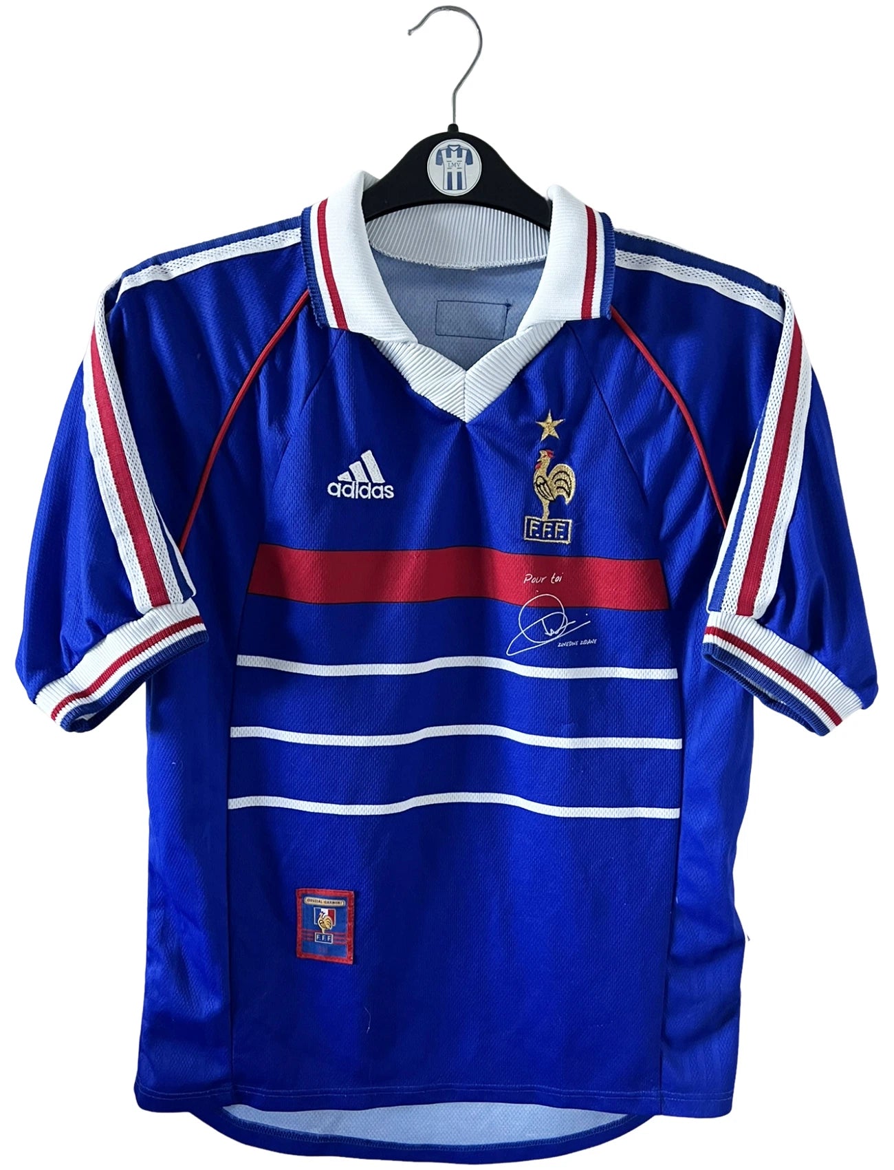 Maillot de foot vintage domicile bleu de l'équipe de France 1998. On peut retrouver l'équipementier Adidas, la signature et le flocage de Zinedine Zidane. Il s'agit d'une magnifique pièce de collection.