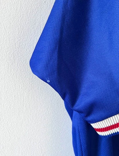 Maillot de foot vintage domicile bleu de l'Equipe de France 1998. On peut retrouver l'équipementier Adidas. Le maillot est floqué du numéro 10 Zinedine Zidane. Il s'agit d'un maillot authentique d'époque.