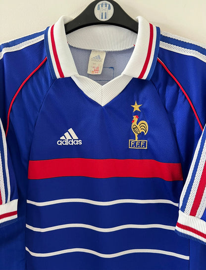 Maillot foot vintage domicile equipe de france 1998 bleu blanc et rouge. On peut retrouver l'équipementier adidas. Le maillot est floqué du numéro 10 Zinedine Zidane. Il s'agit d'un maillot authentique d'époque vendu avec son short d'époque.