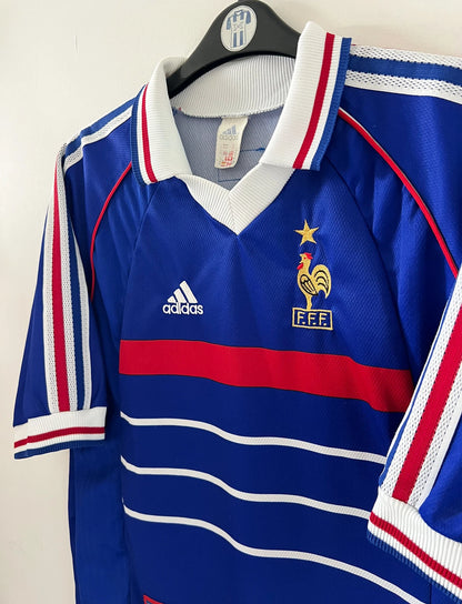 Maillot foot vintage domicile equipe de france 1998 bleu blanc et rouge. On peut retrouver l'équipementier adidas. Le maillot est floqué du numéro 10 Zinedine Zidane. Il s'agit d'un maillot authentique d'époque vendu avec son short d'époque.