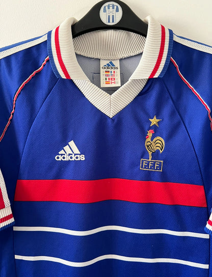 Maillot de foot vintage domicile bleu de l'Equipe de France 1998. On peut retrouver l'équipementier Adidas. Le maillot est floqué du numéro 10 Zinedine Zidane. Il s'agit d'un maillot authentique d'époque.