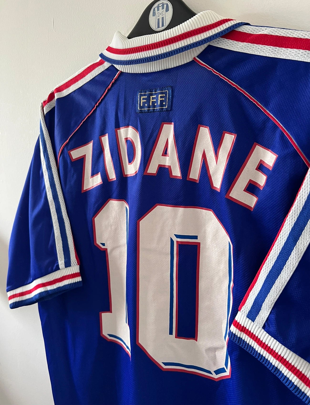 Maillot de foot vintage domicile bleu de l'équipe de france 1998. On peut retrouver l'équipementier Adidas. Le maillot est floqué du numéro 10 Zinedine Zidane. Il s'agit d'un maillot authentique d'époque.