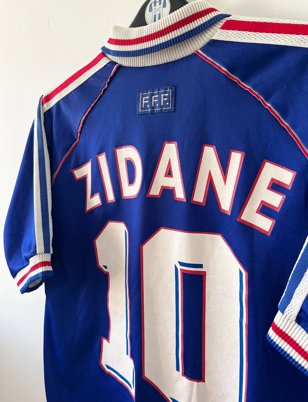 Maillot de foot vintage domicile bleu de l'Equipe de France 1998. On peut retrouver l'équipementier Adidas. Le maillot est floqué du numéro 10 Zinedine Zidane. Il s'agit d'un maillot authentique d'époque.