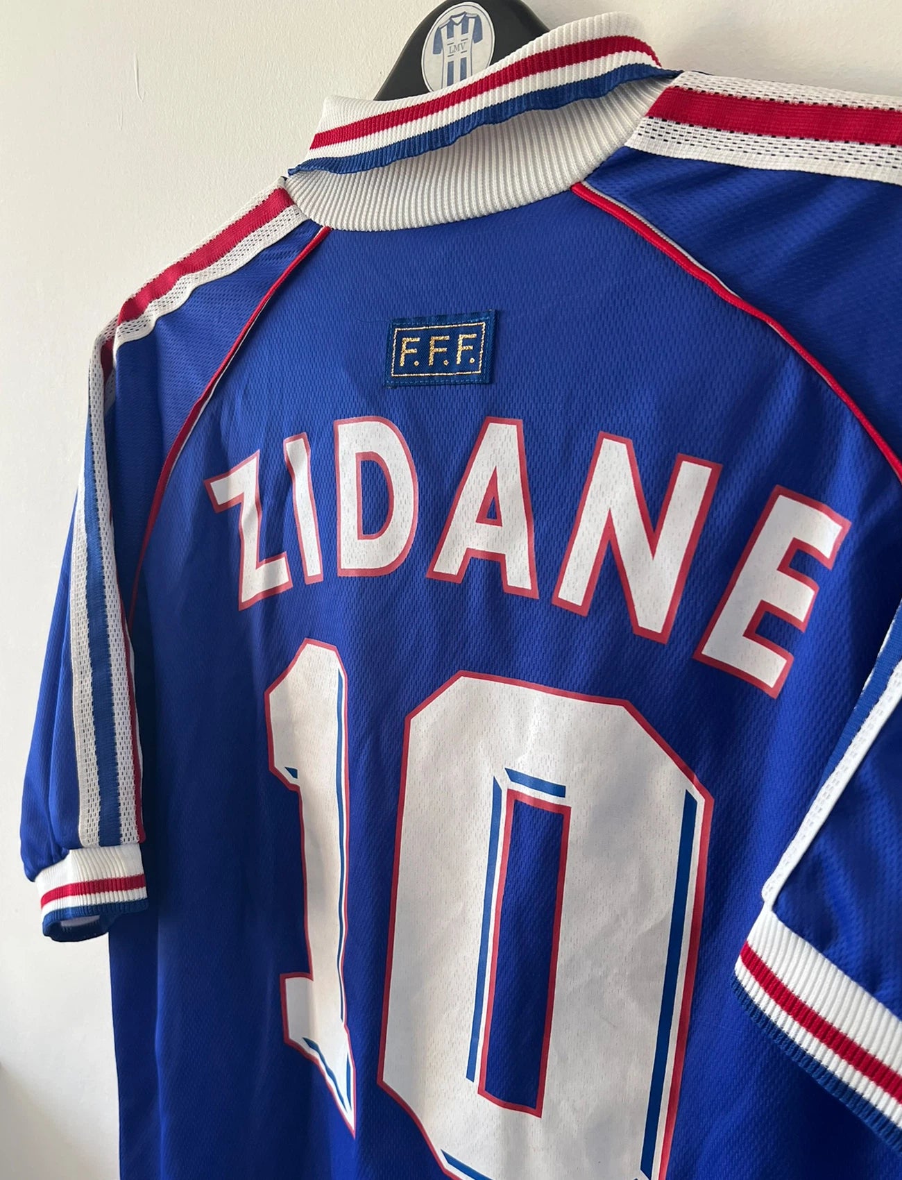Maillot de foot vintage domicile bleu de l'équipe de france 1998. On peut retrouver l'équipementier Adidas. Le maillot est floqué du numéro 10 Zinedine Zidane. Il s'agit d'un maillot authentique d'époque.