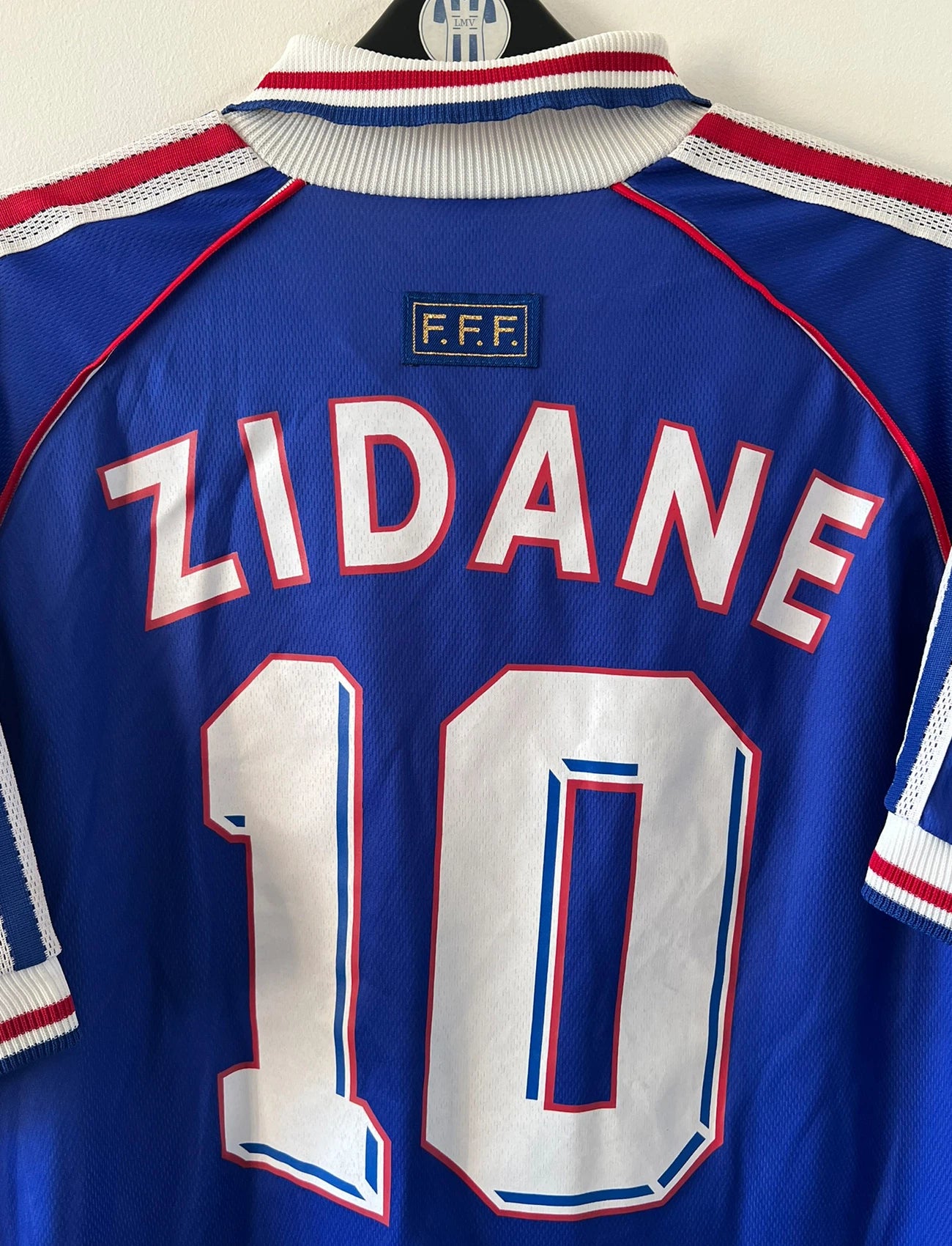 Maillot de foot vintage domicile bleu de l'équipe de france 1998. On peut retrouver l'équipementier Adidas. Le maillot est floqué du numéro 10 Zinedine Zidane. Il s'agit d'un maillot authentique d'époque.