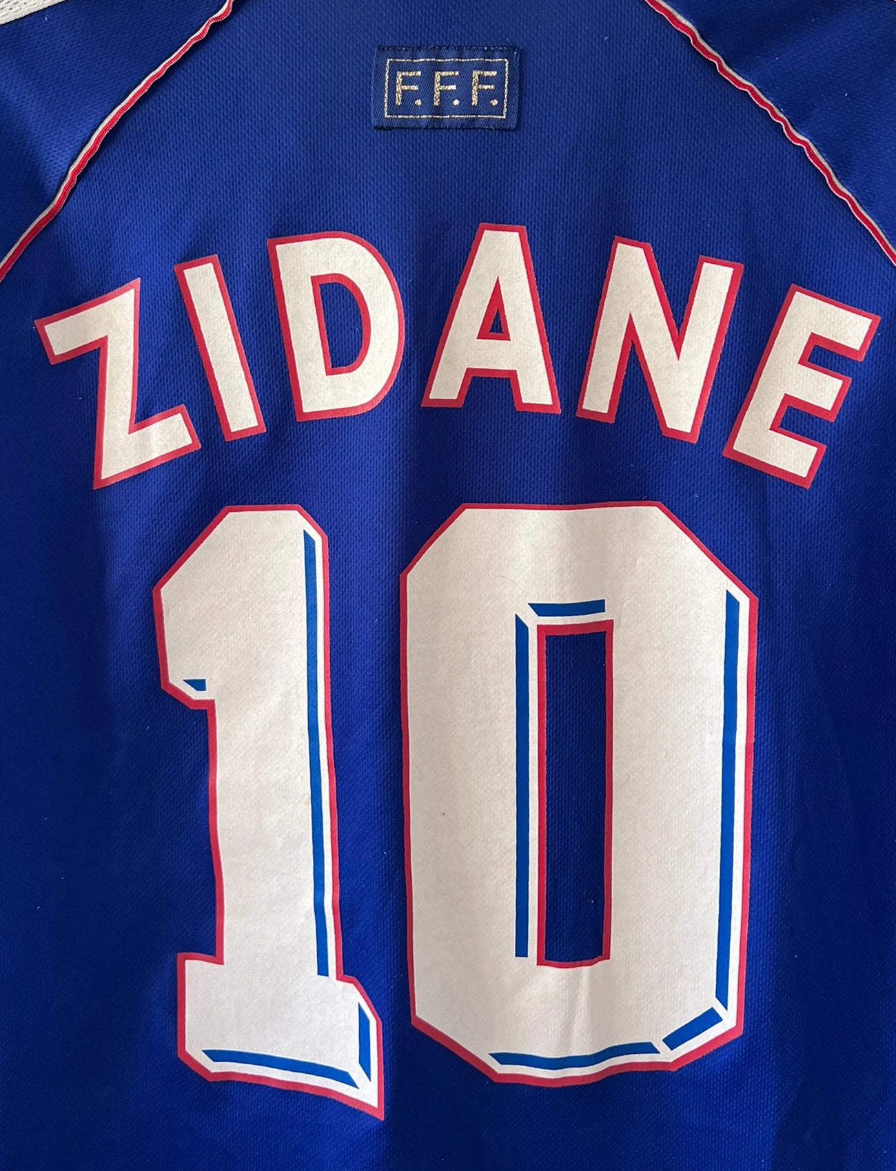 Maillot de foot vintage domicile bleu de l'Equipe de France 1998. On peut retrouver l'équipementier Adidas. Le maillot est floqué du numéro 10 Zinedine Zidane. Il s'agit d'un maillot authentique d'époque.