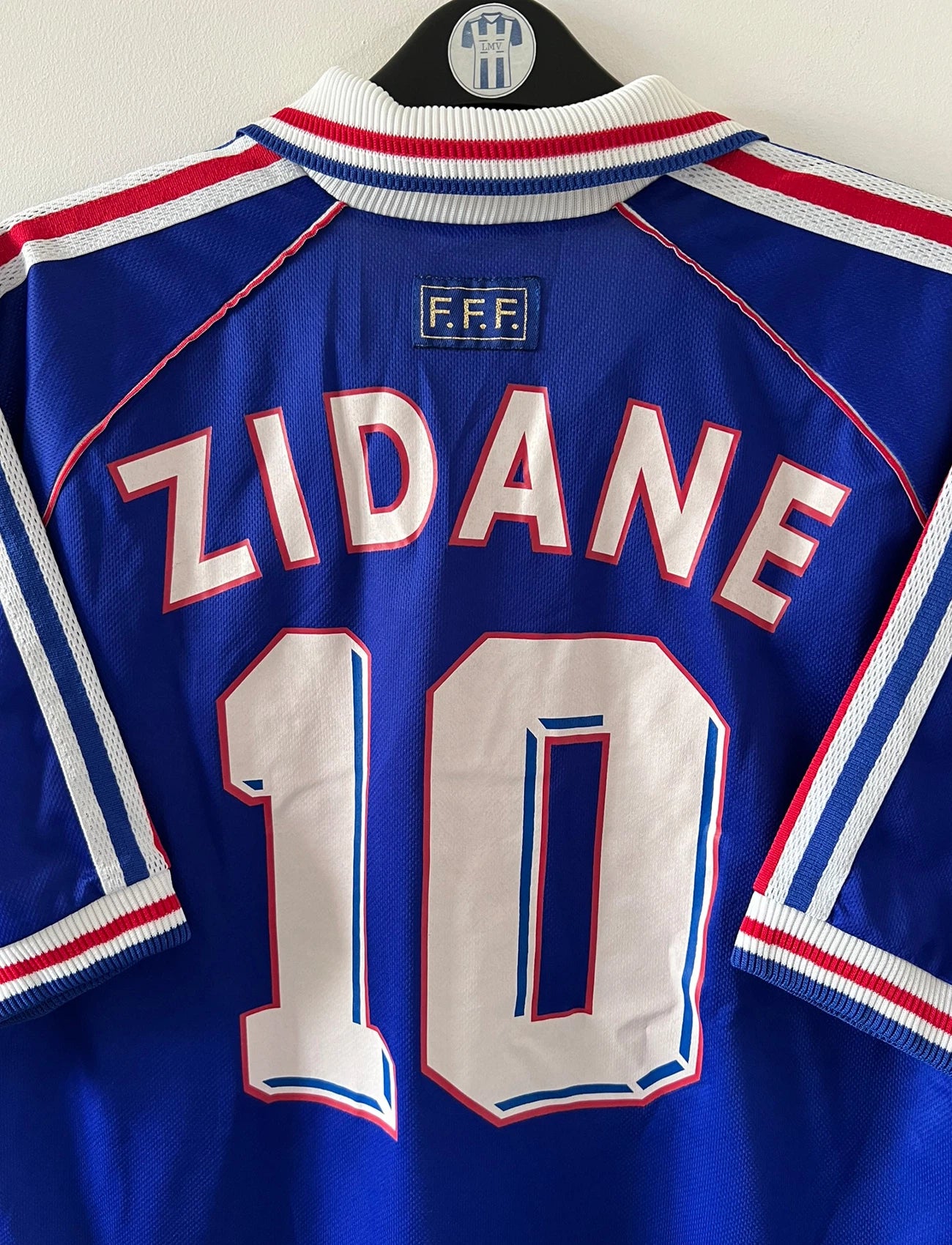 Maillot de foot vintage domicile bleu de l'équipe de france 1998. On peut retrouver l'équipementier Adidas. Le maillot est floqué du numéro 10 Zinedine Zidane. Il s'agit d'un maillot authentique d'époque.