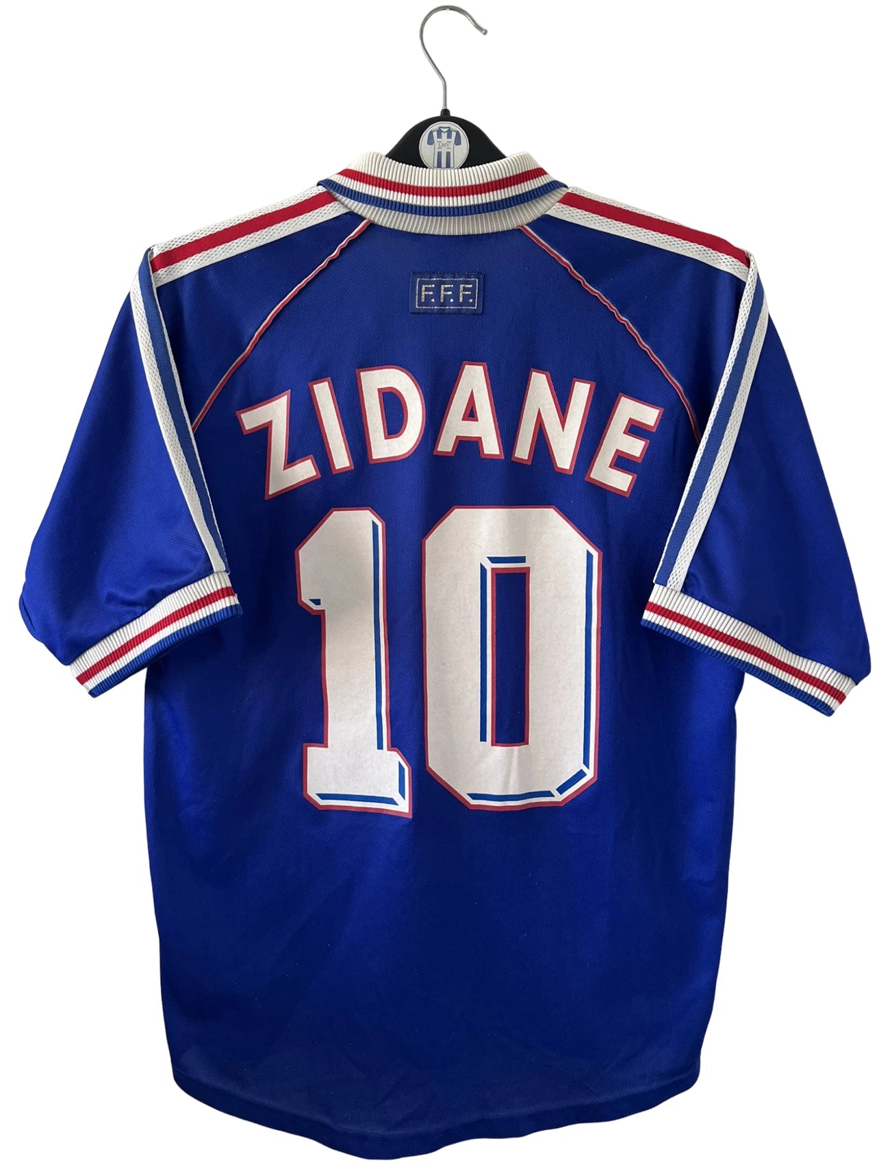 Maillot de foot vintage domicile bleu de l'Equipe de France 1998. On peut retrouver l'équipementier Adidas. Le maillot est floqué du numéro 10 Zinedine Zidane. Il s'agit d'un maillot authentique d'époque.