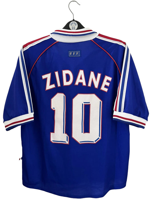 Maillot foot vintage domicile equipe de france 1998 bleu blanc et rouge. On peut retrouver l'équipementier adidas. Le maillot est floqué du numéro 10 Zinedine Zidane. Il s'agit d'un maillot authentique d'époque vendu avec son short d'époque.