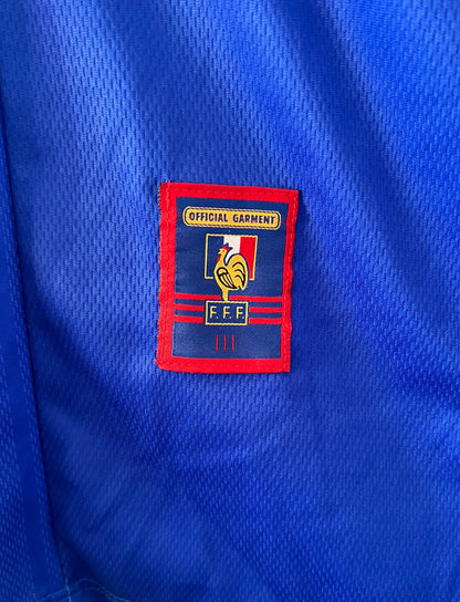 Maillot de foot vintage domicile bleu de l'équipe de france 1998. On peut retrouver l'équipementier Adidas. Le maillot est floqué du numéro 10 Zinedine Zidane. Il s'agit d'un maillot authentique d'époque.