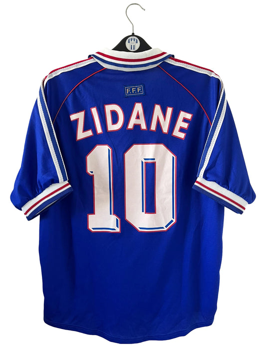 Maillot de foot vintage domicile bleu de l'équipe de france 1998. On peut retrouver l'équipementier Adidas. Le maillot est floqué du numéro 10 Zinedine Zidane. Il s'agit d'un maillot authentique d'époque.
