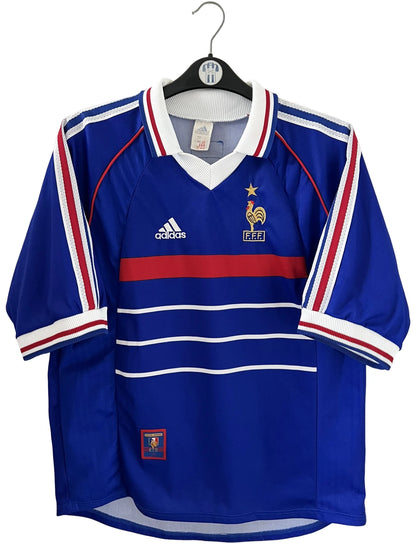 Maillot foot vintage domicile equipe de france 1998 bleu blanc et rouge. On peut retrouver l'équipementier adidas. Le maillot est floqué du numéro 10 Zinedine Zidane. Il s'agit d'un maillot authentique d'époque vendu avec son short d'époque.