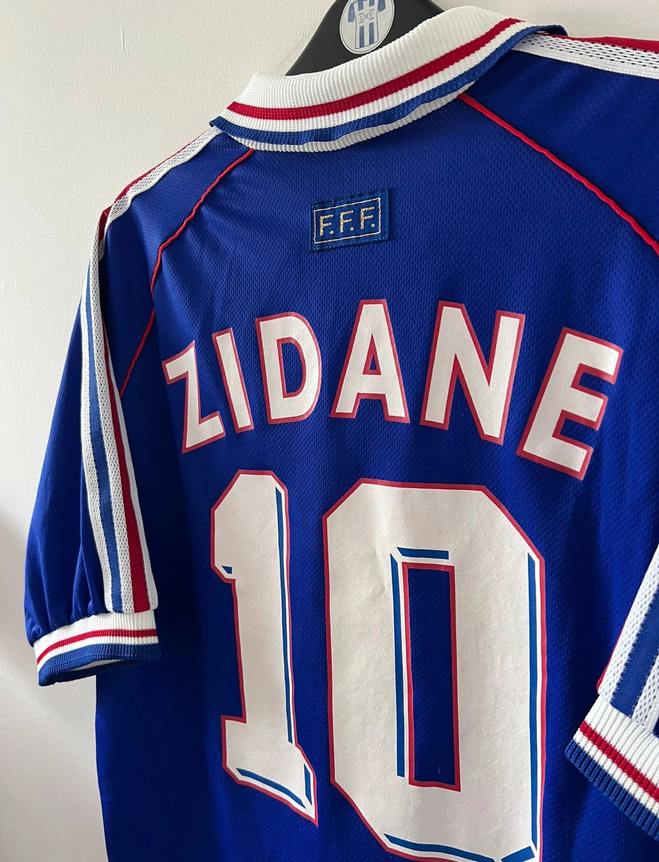 Maillot de foot vintage domicile bleu de l'équipe de france 1998. On peut retrouver l'équipementier Adidas. Le maillot est floqué du numéro 10 Zinedine Zidane. Il s'agit d'un maillot authentique d'époque.