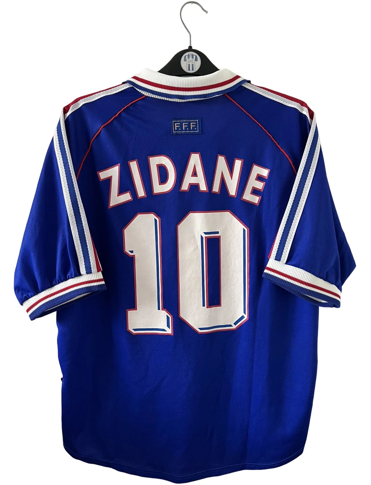 Maillot de foot vintage domicile bleu de l'équipe de france 1998. On peut retrouver l'équipementier Adidas. Le maillot est floqué du numéro 10 Zinedine Zidane. Il s'agit d'un maillot authentique d'époque.