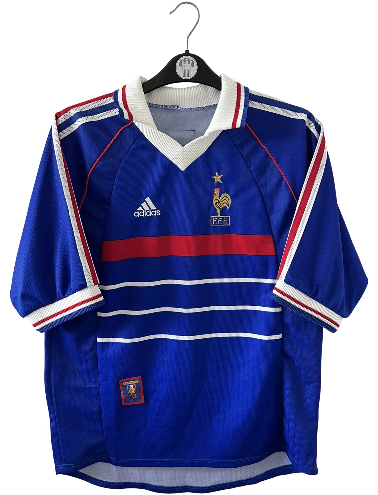 Maillot de foot vintage domicile bleu de l'équipe de france 1998. On peut retrouver l'équipementier Adidas. Le maillot est floqué du numéro 10 Zinedine Zidane. Il s'agit d'un maillot authentique d'époque.