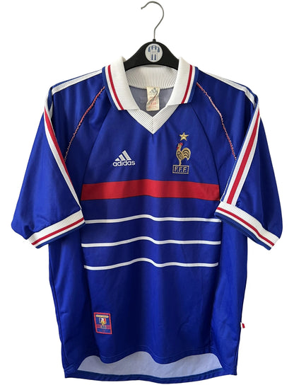 Maillot de foot vintage domicile bleu blanc et rouge de l'équipe de france 1998. On peut retrouver l'équipementier Adidas. Il s'agit d'un maillot authentique d'époque.