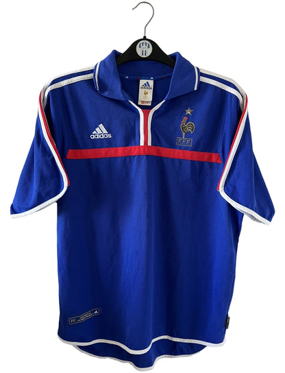 Maillot de foot vintage domicile bleu de l'équipe de france 2000. On peut retrouver l'équipementier Adidas. Il s'agit d'un maillot authentique d'époque.
